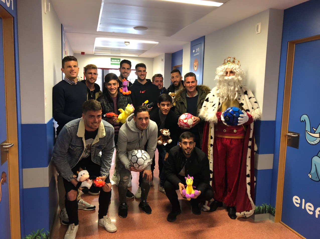 Jugadores y Cuerpo técnico de la primera plantilla acompañan al Rey Melchor a llevar regalos a los niños ingresados en el Hospital Rafael Méndez